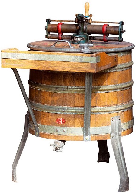 The picture shows a tub washing machine from 1950. You can see a wooden tub on metal feet and a metal repair on the lid.