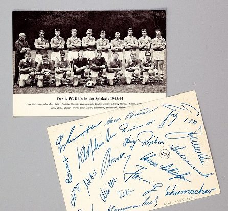 Das Bild zeigt ein Foto der Mannschaft des 1. FC Kölns aus dem Jahr 1963. Auf der Rückseite haben alle Mitglieder unterschrieben.