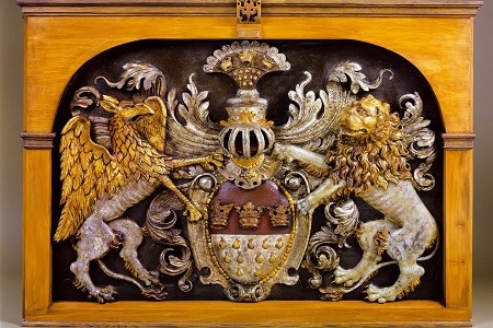 Man sieht das Kölner Wappen aus Holz. Einige Elemente sind vergoldet.