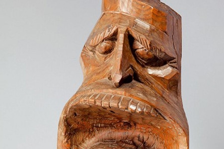 Man sieht das Gesicht einer Holzfigur mit einem sehr großen offenen Mund.