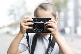 Zu sehen ist ein Kind mit einer Kamera in der Hand.