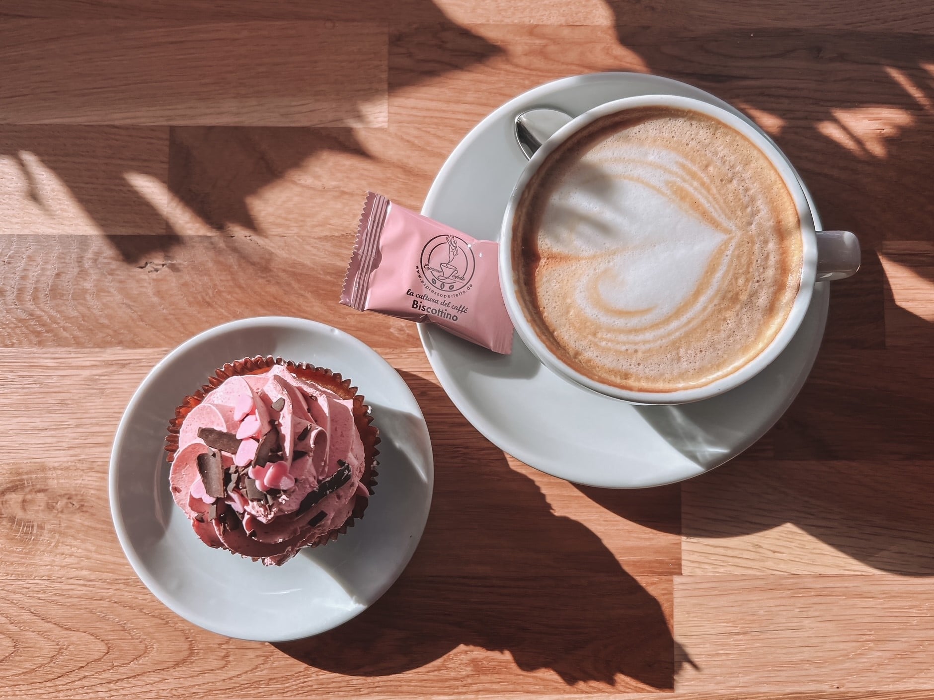 Man sieht eine OnTop-Aufnahme einer Tasse Kaffee und eines Muffins.