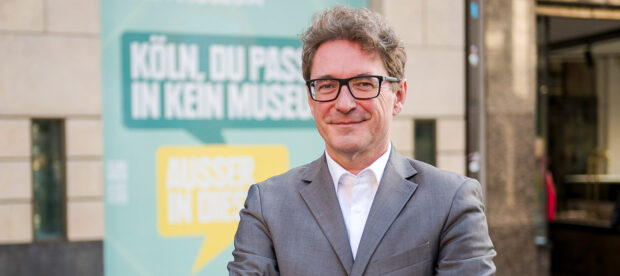 Auf dem Bild ist Dr. Matthias Hamann, der neue Leiter des Kölnischen Stadtmuseums zu sehen. Er steht vor dem Gebäude des Museums und lächelt in die Kamera.