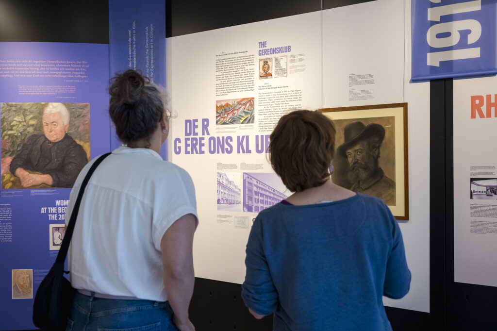 Hand hält ein Smartphone mit dem Multimediaguide vor einen Wandtext der Ausstellung