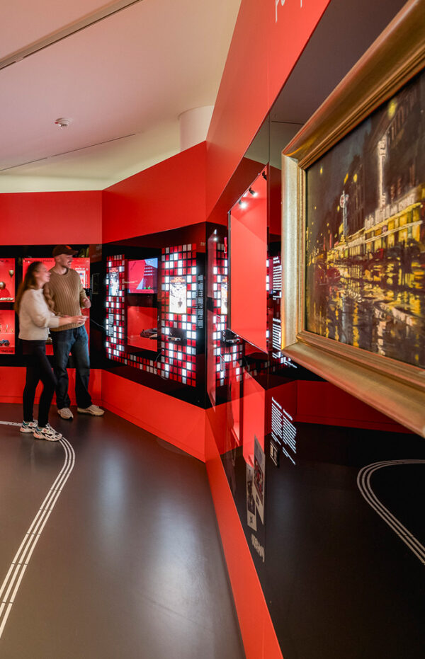 Roter Ausstellungsgang mit einem großformatigen Gemälde einer nächtlichen Straße