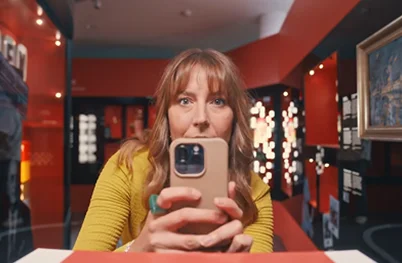 Eine Frau im gelben Pullover macht mit ihrem Smartphone ein Foto für Instagram