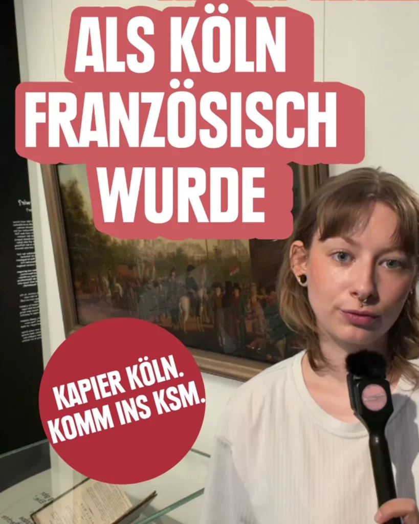 Beitrag „Als Köln französisch wurde“, dazu eine Moderatorin mit Mikrofon vor einem Gemälde